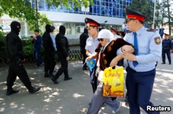 Полицейские ведут задержанную участницу акции протеста по земельному вопросу. Алматы, 21 мая 2016 года.