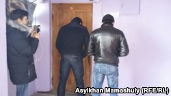 Полицейские, стоящие спиной, блокируют дверь в офис редакции оппозиционного сайта Nakanune.kz, где в это время происходит обыск. Алматы, 18 декабря 2015 года.